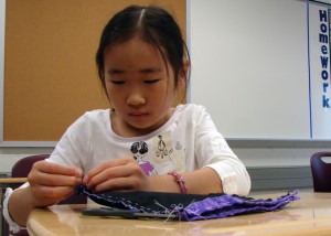 Cindy Liu a 4th grader at Smithland Elementary finishes up the base of her purse at the It's A Stitch class in the Summer Enrichment program at Skyline Middle School. This class has 11 girls and they have been working hard on purses that they are hand sewing. Photo by Lily Harmison
